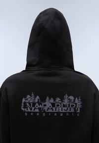 Zwarte hoodie met een grote grijze afbeelding van bomen en de tekst "NAPAPIJRI geographic" op de achterkant. Zachte stof, met capuchon ontwerp.