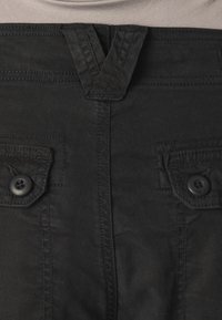 Black cotton pants with a flat front, two buttoned front pockets, and belt loops. Fabric is smooth with visible stitching details.