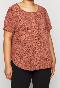 Krátký rukáv v barvě rez s černým skvrnitým vzorem, měkká textura, kulatý výstřih a zakřivený lem, v kombinaci s černými kalhotami.