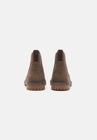Botine negre din suede cu panouri elastice laterale maro, fire de prindere cu textură și tălpi din cauciuc texturat. Branding minimal pe laterale.
