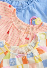 Drei Kinderoberteile: eines hellblau, eines pink mit Streifen und Obstmotiven und eines pastellgestreift mit floralen Designs. Alle haben einen runden Halsausschnitt.