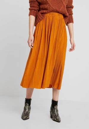 Faltenrock in lebhaftem Orange bis zur Mitte der Wade mit gerafftem Bund, kombiniert mit strukturierten schwarzen Stiefeletten mit Schlangenprint-Muster.