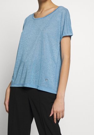 Jasnoniebieska bluzka z krótkim rękawem, wykonana z miękkiego, teksturowanego materiału o luźnym kroju. Posiada okrągły dekolt i mały detal z logo na dolnym brzegu.