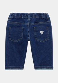 Pantalones cortos de mezclilla azul marino con cintura elástica, dos bolsillos traseros y un parche con logo. Dobladillo con vuelta y detalle de costura en azul claro.