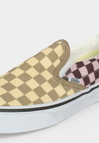 Κοντινή λήψη παπουτσιού Vans slip-on με μπεζ και καφέ καρό μοτίβο μπροστά και ροζ και καφέ καρό στο πλάι.