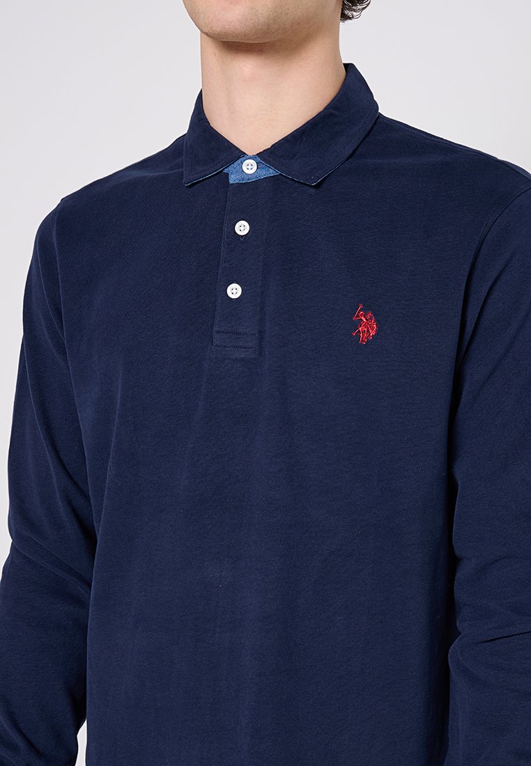 Dunkelblaues Langarm-Polohemd aus Baumwolle, mit einem spitzen Kragen im Denim-Look und drei weißen Knöpfen, versehen mit einem roten Logoemblem.