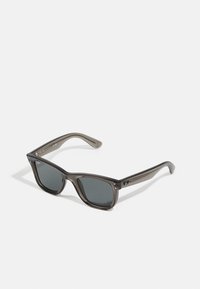 Ochelari de soare gri închis, cu o ramă rectangulară groasă din plastic translucid. Au lentile gri și detalii discrete ale mărcii pe braț.