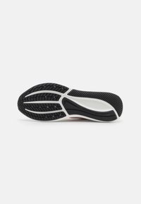 Suela exterior de goma negra con un patrón de tracción multidireccional y entresuela blanca. Presenta una textura suave y bordes curvados para una mejor sujeción.