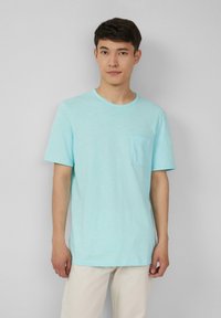 Lichtblauw t-shirt met korte mouwen, ronde hals en een borstzak aan de linkerkant, gemaakt van zachte stof. Eenvoudig ontwerp met een relaxte pasvorm.