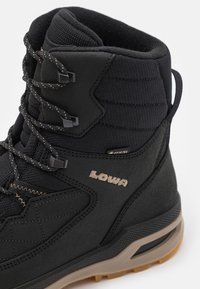 Schwarze Wanderschuhe mit strukturiertem Obermaterial, verstärktem Knöchelbereich und GORE-TEX-Branding. Schnürsenkel mit metallischen Akzenten und gemustertem Detail.