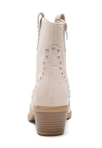 Stivaletto in suede beige con borchie metalliche decorative, chiusura con zip sul retro e tacco impilato. Finitura strutturata con suola liscia.