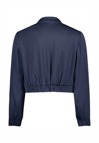 Veste courte bleu marine avec manches longues, poignets et taille élastiqués, vue de dos.