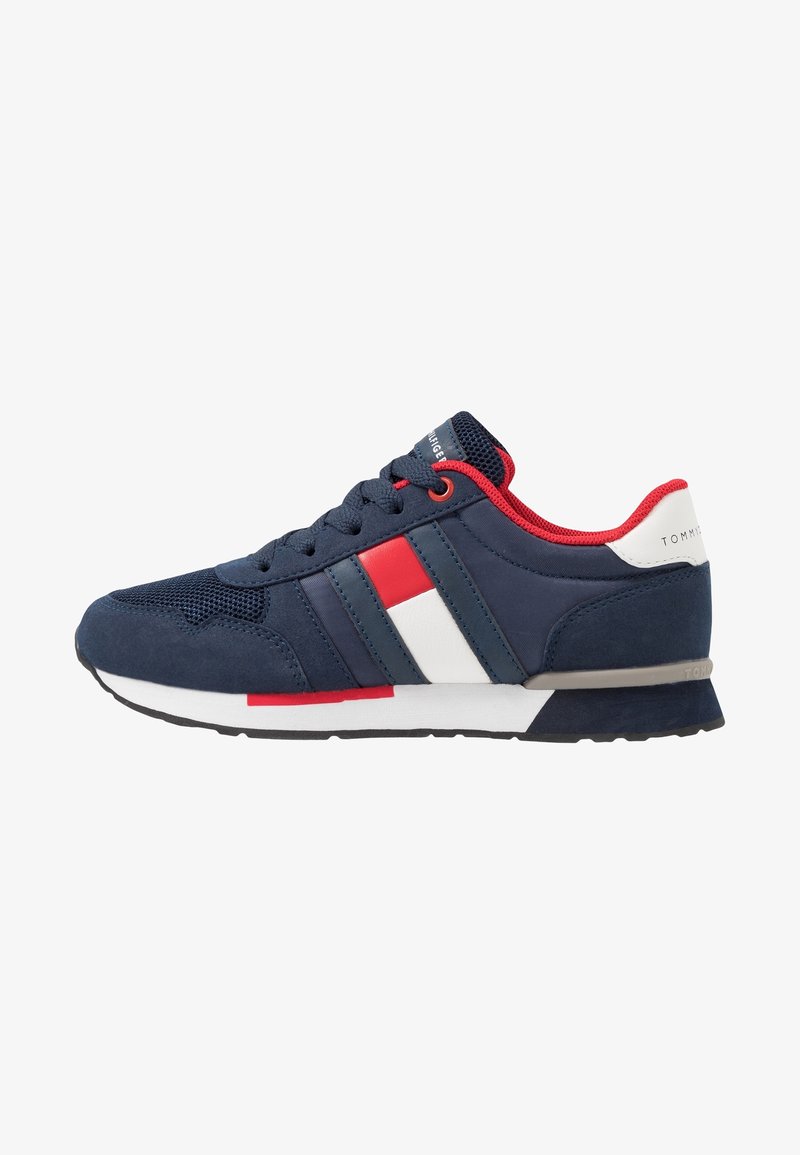 Baskets bleu marine avec des rayures rouges et blanches, une doublure intérieure rouge, un détail blanc au talon et une semelle blanche et noire.