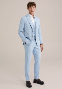 Ljust blå kostym med smal passform, notch-lapel och två knappar. Innehåller en väst, vit skjorta och mörkbruna loafers. Slät textur.