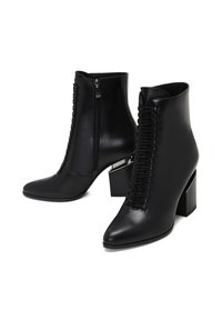 Botas de piel negra hasta el tobillo con tacón cuadrado, cuentan con un cierre lateral y un detalle de cordones en la parte delantera, textura suave y diseño de punta afilada.