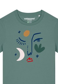 T-shirt en coton vert ornée d'un design de visage abstrait avec des lèvres rouges, une feuille vert olive, une lune croissante rose et des accents graphiques colorés.