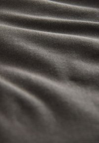 Gråt tekstil med en glat, let struktureret overflade, der har synlige folder og krøller, hvilket indikerer et blødt og fleksibelt materiale.