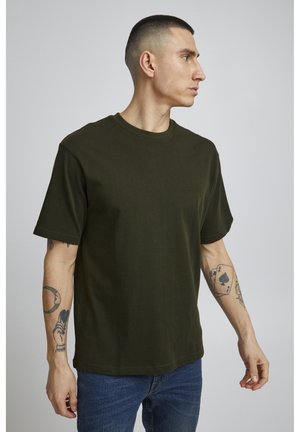 Mørkegrøn t-shirt med rund halsudskæring og korte ærmer. Stoffet ser blødt og glat ud, bæres med blå denim jeans.