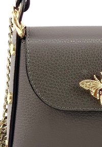 Black leather handbag featuring a stitched flap, gold bee accent, and chain strap with gold hardware. Textured surface with a pebbled finish.