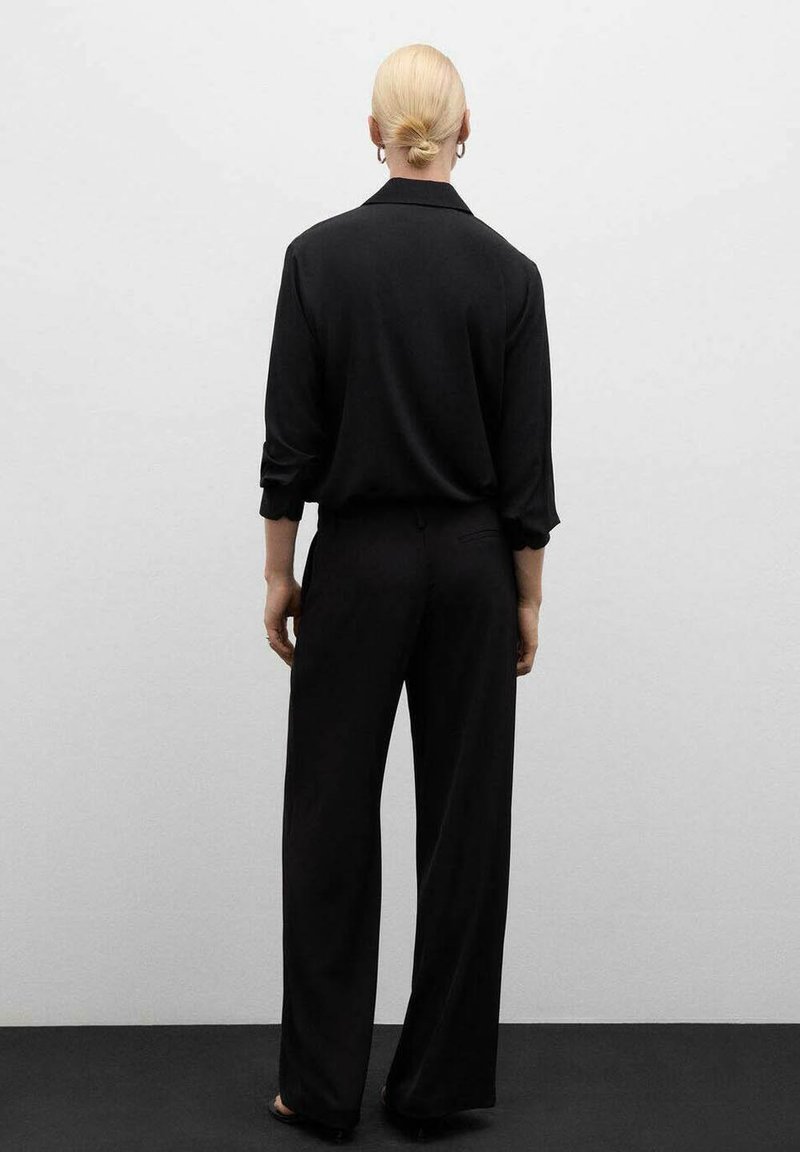 Camisa negra de botones y pantalones. Corte relajado, mangas largas y diseño de pierna recta. Textura suave, estilo minimalista y sin patrones visibles.