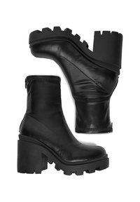 Melnas ādas potītes zābakus ar masīvu platformu, kam ir teksturēta virsma, diagonālas šuves un sānu rāvējslēdzis vieglai uzvilkšanai.