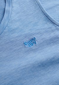 Lichtblauw mouwloos shirt van zacht materiaal, met een v-hals ontwerp en een geborduurd "Superdry" logo in bijpassend blauw.