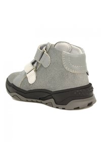 Stivaletto alla caviglia in suede grigio con cinturini in Velcro bianchi e suola in gomma nera testurizzata. Presenta un colletto imbottito e dettagli grigi lisci.