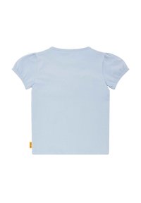 Camiseta de manga corta azul claro con mangas abullonadas, escote redondo y corte recto. Presenta una pequeña etiqueta de marca amarilla en el dobladillo.