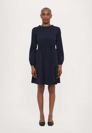 Marineblaues Kleid mit langen Ärmeln, rundem Ausschnitt und einem passenden Gürtel in der Taille. Der plissierte Rockteil verleiht Volumen. Glatte Stoffstruktur.
