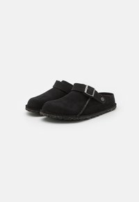 Clog-uri din suede negru, cu un design al vârfului curbat. Prezintă o curea neagră cu o cataramă argintie și o talpă texturată, cu pete. Construcție ușoară.