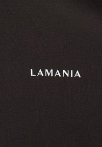 Fekete anyag, bordázott textúrával, alul középen a "LAMANIA" szó kontrasztos fehér színben. Minimalista dizájn.