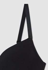 Reggiseno wireless nero in tessuto morbido, con una texture liscia e dettagli con cuciture minime. Spalline regolabili e un design semplice, focalizzato sul comfort.