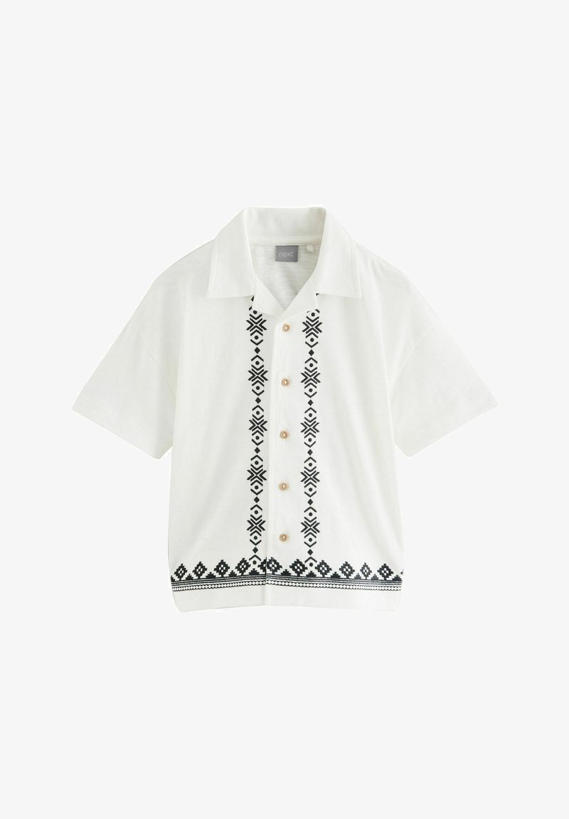 Chemise blanche à manches courtes avec boutons sur le devant, bandes brodées géométriques noires sur le devant et le bas, avec un col ouvert.