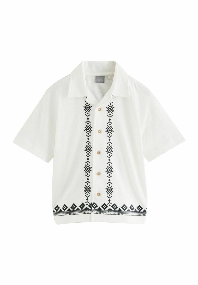 Chemise blanche à manches courtes avec des motifs brodés noirs au centre et à l'ourlet, dotée de boutons beiges et d'un design de col traditionnel.