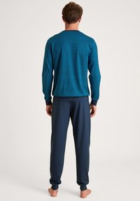 Men's loungewear set featuring a blue patterned long-sleeve top and navy pants, made from soft fabric with elastic cuffs and waistband.