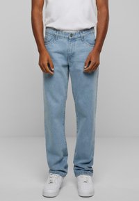 Lys blå denim jeans med rette ben, fem-lomme design, knappelukking og subtil fading, kombinert med hvite sneakers.