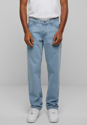 Hellblaue Jeans aus Denim mit geradem Bein, Fünf-Taschen-Design, Knopfverschluss und dezentem Verblassen, kombiniert mit weißen Sneakers.