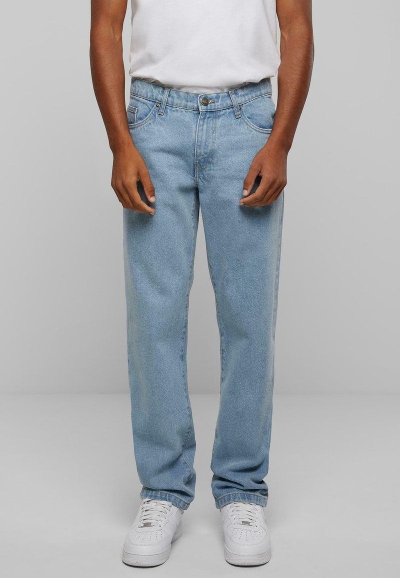 Lys blå denim jeans med rette ben, fem-lomme design, knappelukking og subtil fading, kombinert med hvite sneakers.