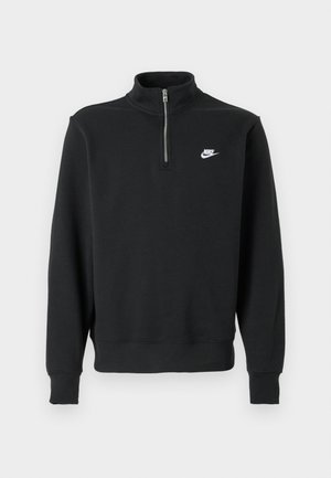 Musta Nike puolen vetoketjun huppari, jossa on korkea kaulus, pitkät hihat ja valkoinen Nike-logo vasemmassa rinnassa tasaisella taustalla.