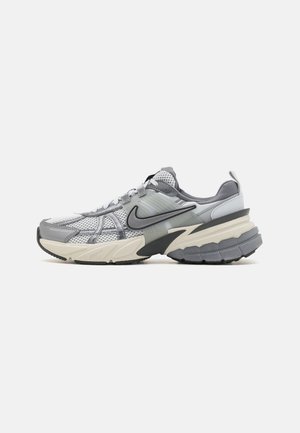 Sneakers Nike in grigio e crema. Upper in rete e sintetico con dettagli testurizzati. Suola in gomma spessa con diversi pattern di battistrada. Design con lacci.