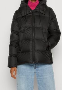 Veste matelassée noire avec capuche, dotée d'une fermeture éclair avant, de boutons-pression et de poignets élastiques. Matériau lisse et brillant avec un motif matelassé.