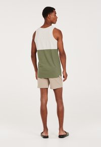 Green and white color-blocked tank top with a loose fit, paired with beige shorts. The tank features a round neck and wide armholes.