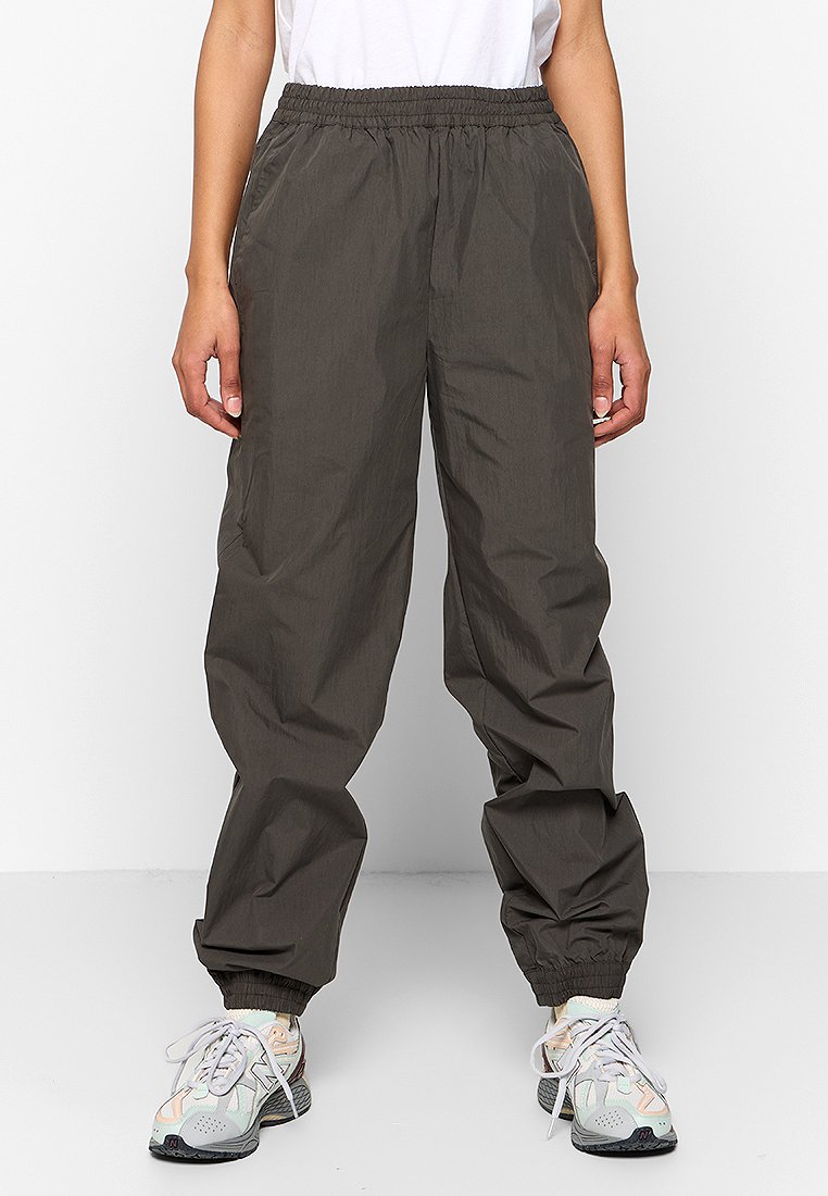 Donkergrijze, lichte, elastische sweatpants met taps toelopende pijpen en elastische boorden, gecombineerd met veelkleurige sportschoenen.