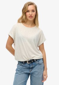 Lichtgrijze, korte mouwen t-shirt met een ronde hals en omgerolde mouwen, gecombineerd met blauwe jeans en een zwarte riem met een zilveren gesp.