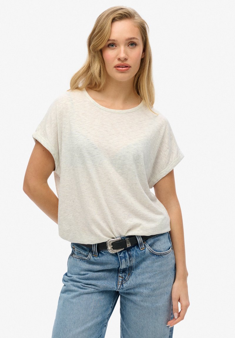 Lichtgrijze, korte mouwen t-shirt met een ronde hals en omgerolde mouwen, gecombineerd met blauwe jeans en een zwarte riem met een zilveren gesp.