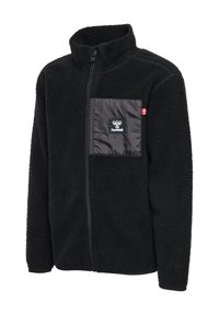 Veste en polaire noire avec un col montant, fermeture éclair frontale et une poche poitrine en nylon noir contrastant avec un logo. Matériau texturé avec des accents lisses.