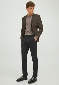 Brown checked blazer over a gray shirt, paired with black trousers and black loafers. Smooth fabric with tailored fit and clean lines.