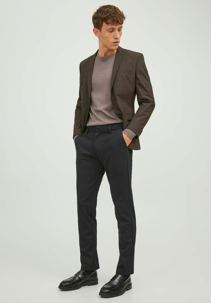 Brown checked blazer over a gray shirt, paired with black trousers and black loafers. Smooth fabric with tailored fit and clean lines.