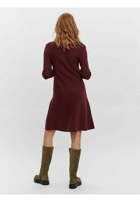 Burgundy stickad klänning med långa ärmar och utsvängd nederkant. Kombinerad med olivgröna knähöga stövlar och svarta sulor. Enkelt design, inga synliga mönster.