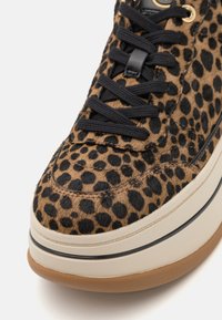 Baskets à imprimé léopard avec une surface texturée, semblable à de la fourrure; elles sont dotées de lacets noirs, d'une semelle intermédiaire crème et d'une semelle extérieure en caoutchouc coloris caramel.